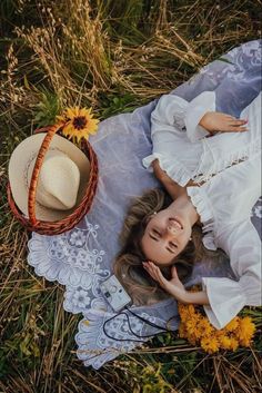 a woman laying on top of a blanket next to a hat