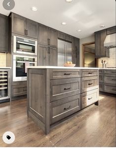 a large kitchen with wooden floors and gray cabinets