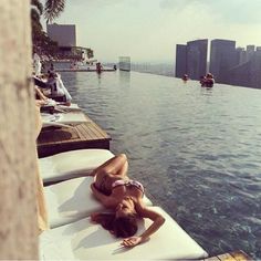 a woman laying on top of a white surfboard next to the edge of a swimming pool