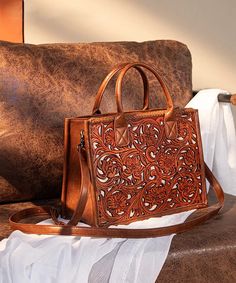 Made of synthetic leather Floral tooled with hand coloring on the front Whipstitch detail Top zipper closure Top handle (Drop: 4") The inside of the bag includes a zippered pocket Detachable and adjustable western purse straps (Drop: 22"-28.5") 12.3"(L) x 5"(W) x 9"(H) Interior Capacity: Medium Elegant Embossed Travel Bag, Elegant Embossed Top Handle Shoulder Bag, Embossed Top Handle Bag For Travel, Embossed Top Handle Travel Bag, Elegant Top Handle Embossed Bag, Elegant Embossed Top Handle Bag, Elegant Embossed Rectangular Bag, Elegant Embossed Tote Bag, Elegant Embossed Bags For Daily Use