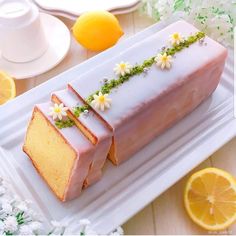 a piece of cake on a white plate with flowers and lemons next to it