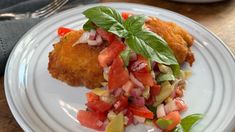 a white plate topped with meat and veggies on top of a wooden table