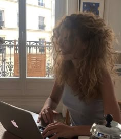 a woman sitting at a table using a laptop computer