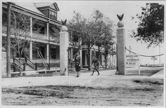 an old black and white photo of two men walking down the street in front of a building