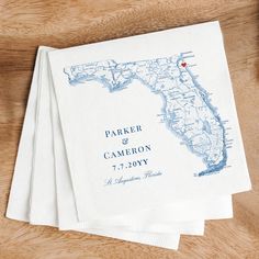 three personalized napkins on top of a wooden table with a map printed on them