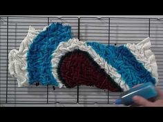 a person is using a blue and white brush to decorate a piece of cake on a wire rack