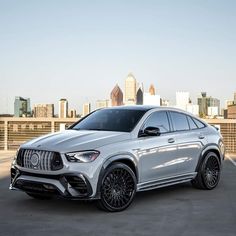 a silver mercedes suv parked in front of a city skyline