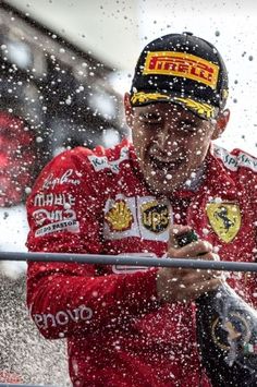 a man in a red racing suit is spraying water on his face