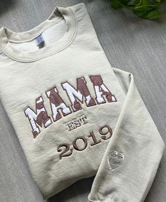 a white sweatshirt with the word mama printed on it, next to a potted plant