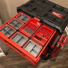 a red tool box filled with tools on top of a wooden floor