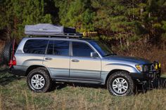 a silver suv parked in the grass near some trees