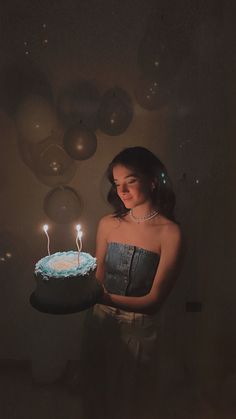 a woman holding a birthday cake with lit candles