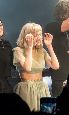 two women standing next to each other in front of a man and woman on stage