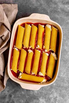 a casserole dish filled with pasta and sauce next to a napkin on the side