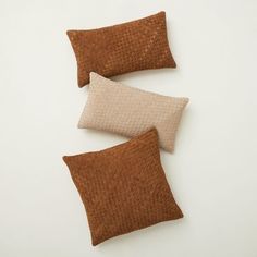 three brown and white pillows sitting on top of a white table next to each other