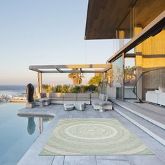 an outdoor area with a pool, lounge chairs and rug on the floor next to it