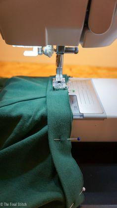 the sewing machine is working on the green material that has been sewn together with it's foot