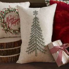 three pillows with christmas trees on them, one has a bow and the other has a present