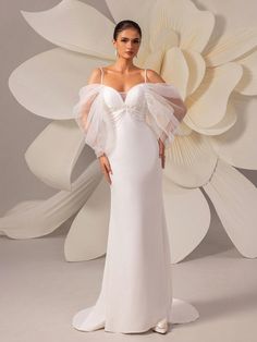 a woman in a white dress standing next to a large flower