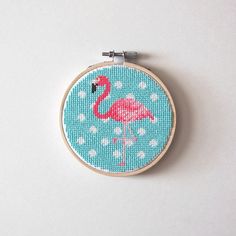 a pink flamingo cross stitched into a blue hoop with white polka dots on it