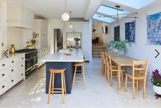 a large kitchen with an island and bar stools in the center, surrounded by white cabinets