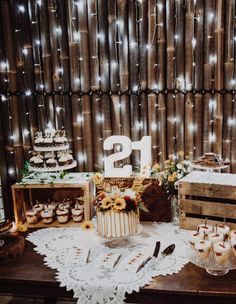 a table topped with cakes and cupcakes on top of a wooden table covered in lights