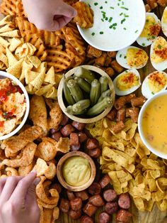 several different types of food are spread out on a wooden table with dips and crackers