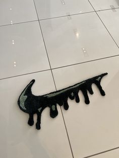 a piece of art that looks like a lizard is on the floor with white tiles