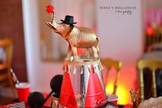 an elephant figurine sitting on top of a red and white cone with a black hat