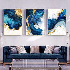 two paintings on the wall above a couch in a living room with blue and gold decor