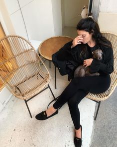 a woman sitting on a chair holding a small dog