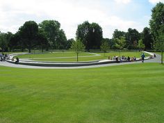 a group of people standing on top of a lush green field next to a park