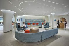 people are sitting in the waiting area of an office with blue couches and chairs