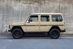 a beige jeep parked in front of a concrete wall