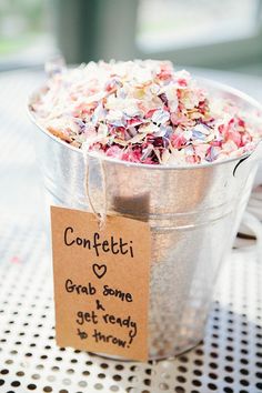 a bucket full of confetti sitting on top of a table next to a sign