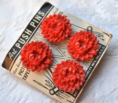 three red flowers are sitting on top of a piece of paper