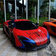 two red and blue sports cars parked next to each other in front of a building