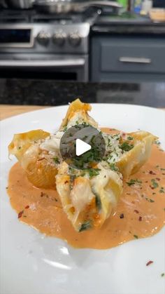 a white plate topped with ravioli covered in grated cheese and sauce on top of a kitchen counter