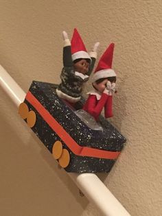 two elfs are sitting on top of a toy train