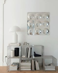 a mirrored shelf with books and magazines on it in front of a wall mounted mirror