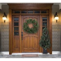 a wooden door with a wreath on the top and two lights at the front entrance