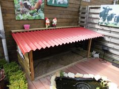 an outdoor area with a water feature and paintings on the wall, including a red roof