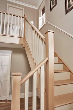 there are pictures on the wall next to the stairs in this house that has been painted white