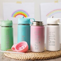 three different colored water bottles sitting on top of a wooden table next to each other