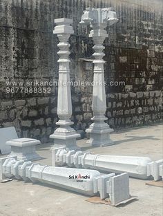 some white marble pillars and benches in front of a brick wall