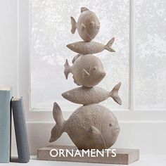 three fish stacked on top of each other in front of a window with the words ornaments above them