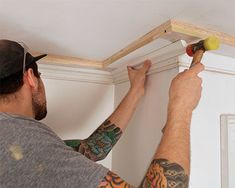 a man is working on the ceiling in his home with some screwdrivers and hammers