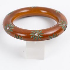 This is part of Chairish’s Costume Jewelry assortment.  A stunning cinnamon-brown Bakelite bracelet bangle. Chunky rounded domed shape with floral carving all around with green paint contrast, complemented with AB crystal rhinestones. Lovely reddish-brown intense color. Measurements: Inside across is 2.50 in diameter (6.3 cm) - outside across is 3.69 in diameter (9.4 cm) - width is 0.63 in wide (1.5 cm) - inner circumference is 8.25 in long (21 cm).  Please see the measurements noted above in th Bakelite Bracelets, Cinnamon Brown, Reddish Brown, Green Paint, Bracelet Bangle, Intense Colors, Crystal Rhinestone, Costume Jewelry, Bangle Bracelets