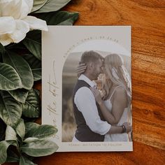 a wedding photo with flowers and greenery around it on top of a wooden table