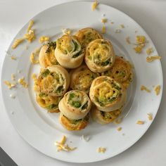 a white plate topped with mini sandwiches covered in cheese and broccoli florets